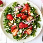 Strawberry kale salad on a white plate.