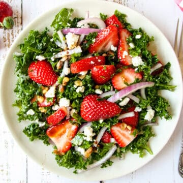 Strawberry kale salad on a white plate.