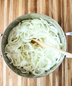 Sliced onions in a stockpot ready to be caramelized.