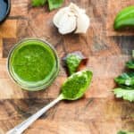 A jar of green sauce on a table with a spoon