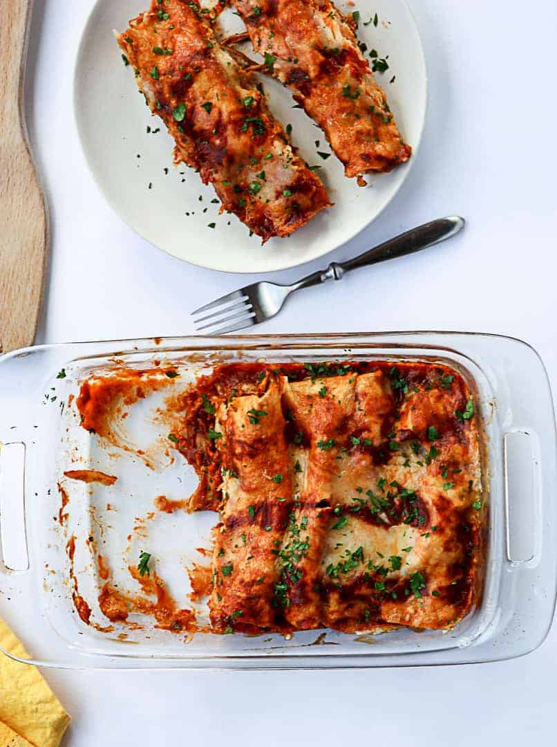 Pan of enchiladas and two enchiladas on a plate with a fork