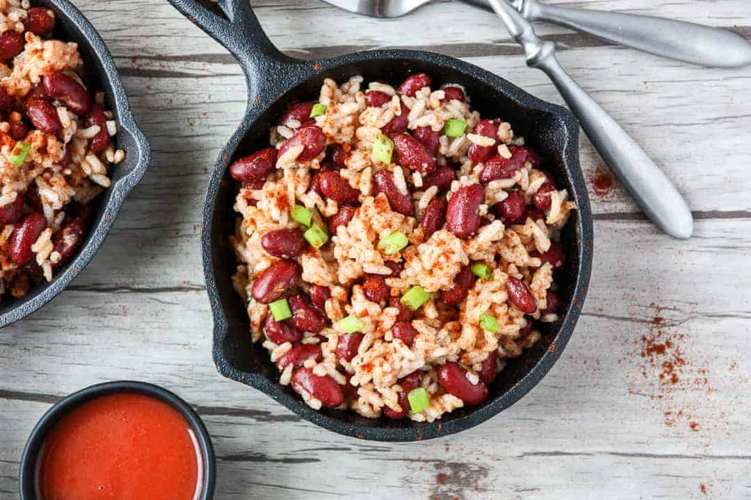 Red beans and rice in small black skillet on wooden table