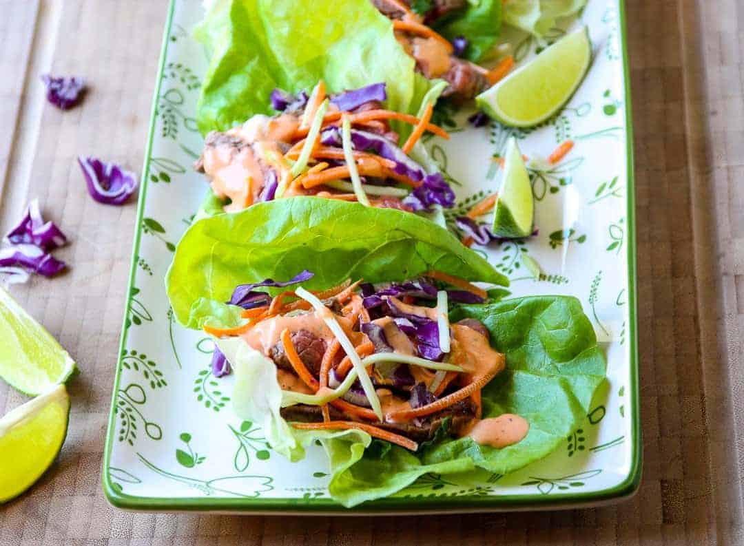 Lettuce wraps on a platter, with lime wedges