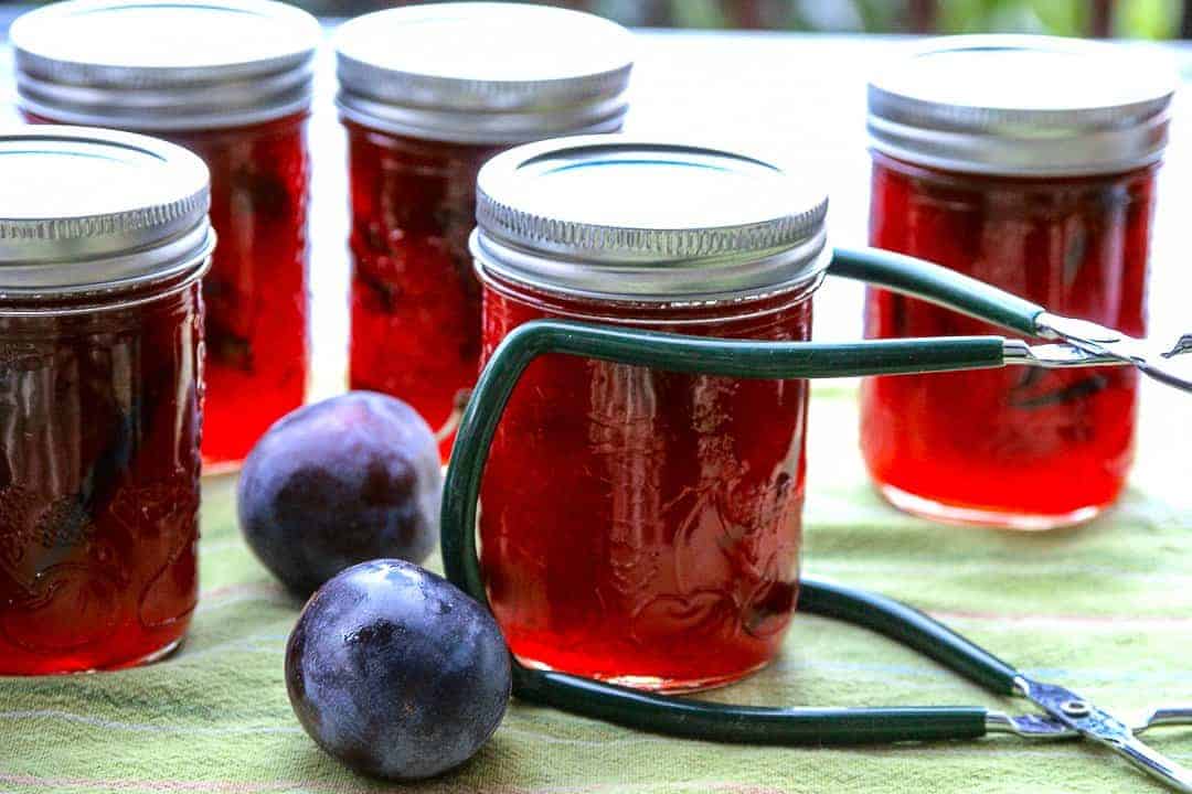 Five jars of preserves on a green kitchen towel.