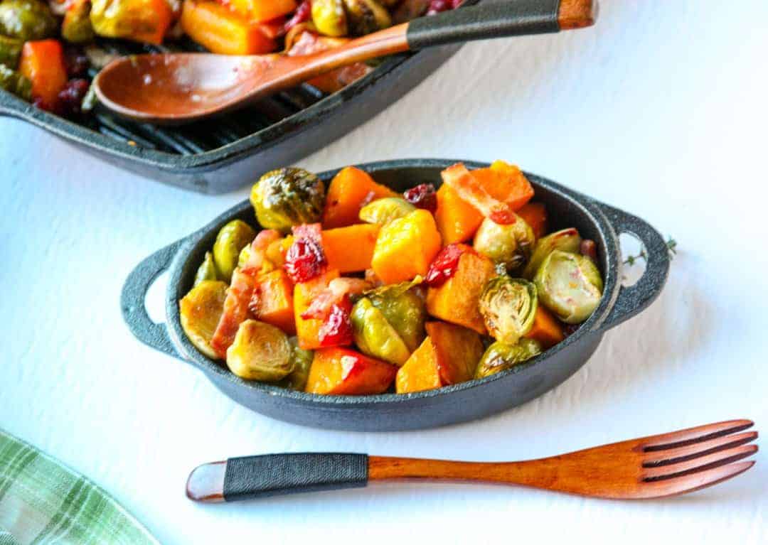 A bowl of food on a table, with Squash and Brussels sprouts