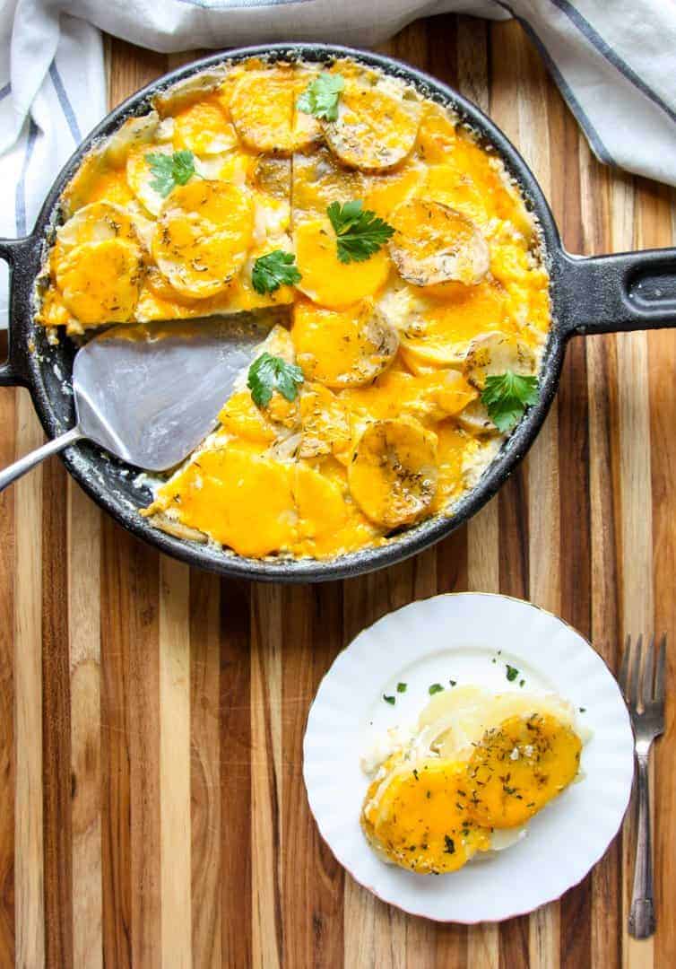 A pan of potatoes with cheese on a wooden table