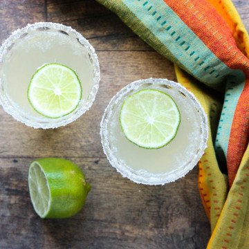 Two cocktails on a table with lime