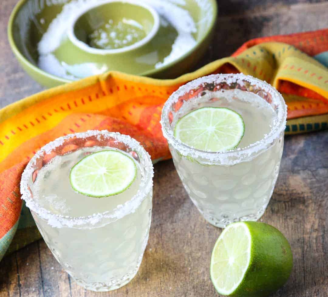 2 salt rimmed glasses of prosecco margarita cocktails with lime slices