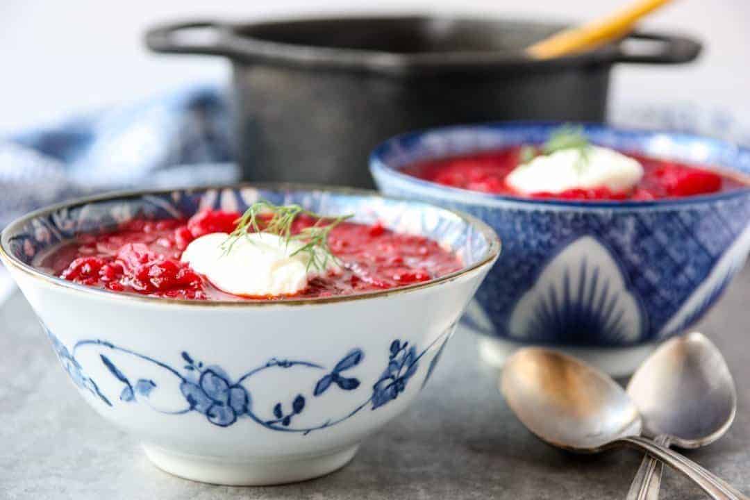 black pot and two blue and white bowls filled with Ukrainian borscht 