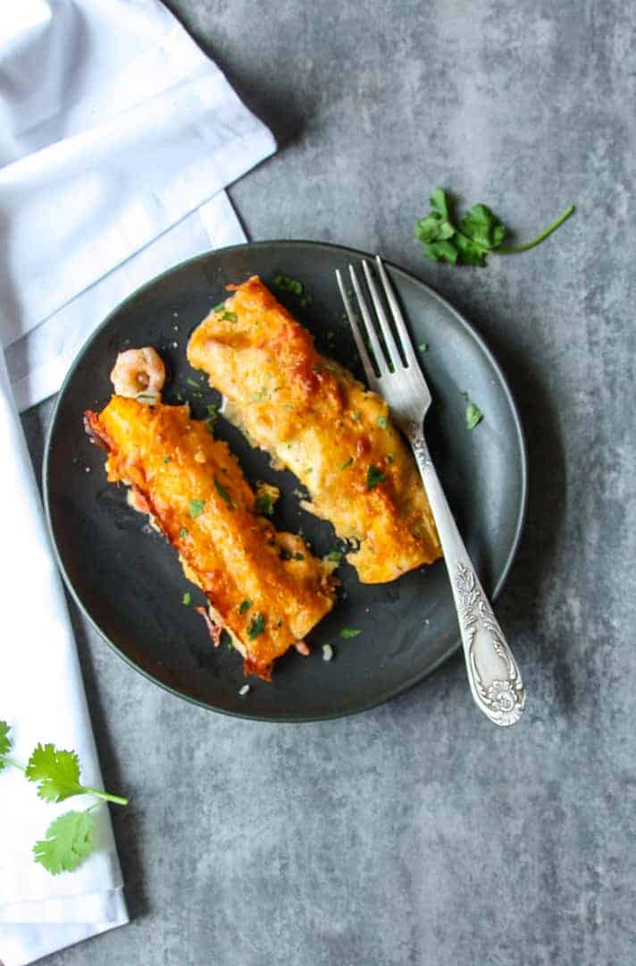 A plate of food with a fork, with Seafood Enchiladas