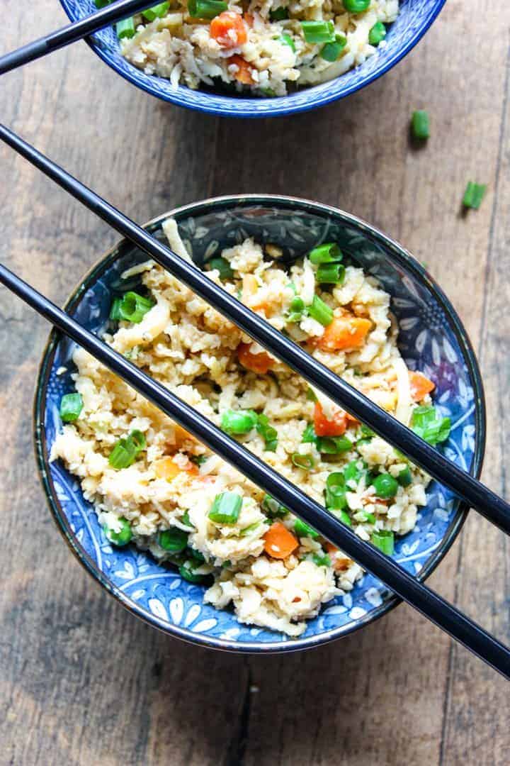 A bowl of food with rice and vegetables, with chopsticks