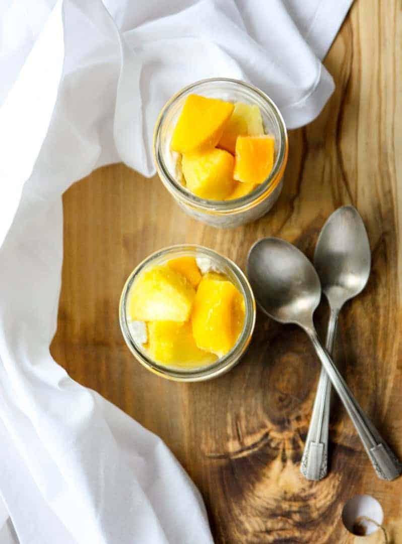 Two jars of pudding with two spoons on a table