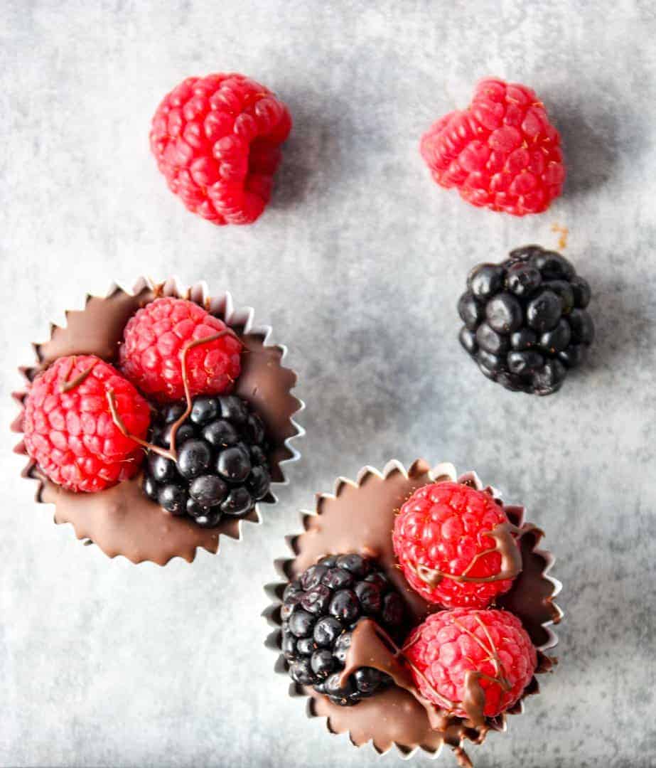 Close up top down shot of two homemade chocolate berry cups with raspberries and blackberries