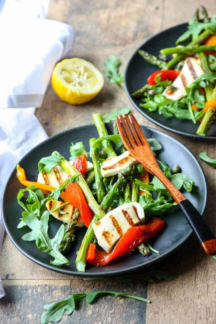 two black plates with roasted asparagus & pepper salad