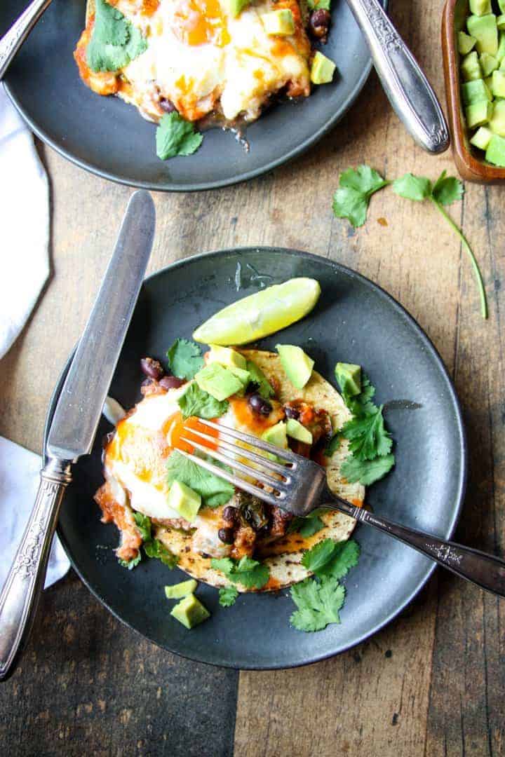 A plate of huevos rancheros on a table, with a knife and fork.