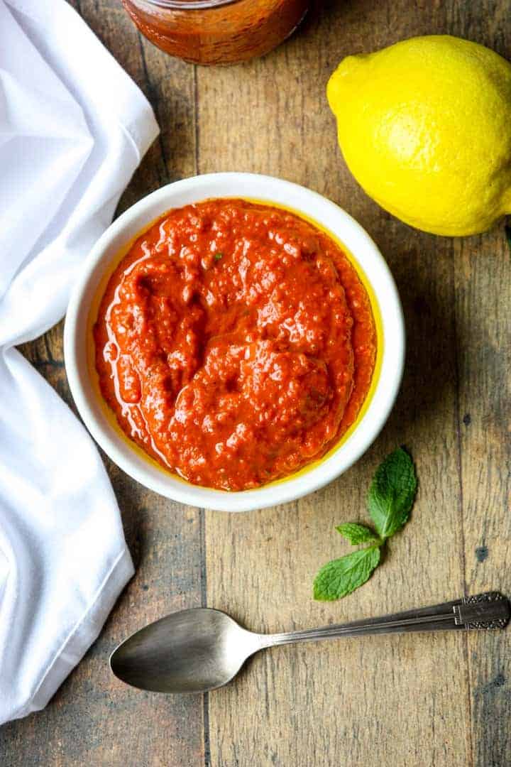 A bowl of red sauce sitting on top of a wooden table