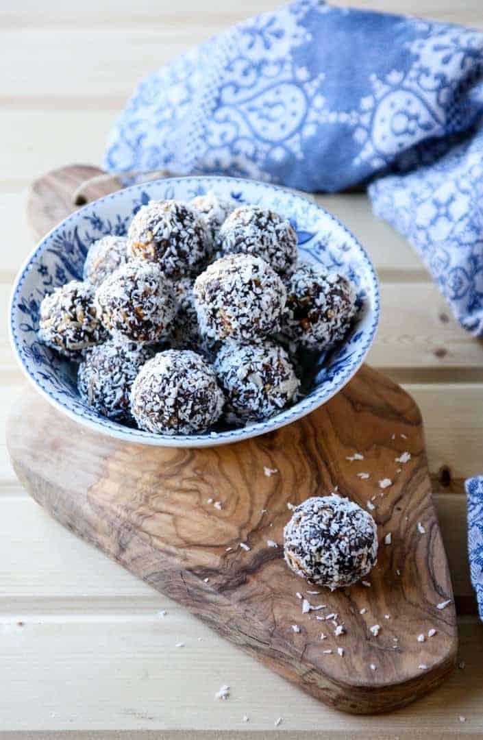 Prune Energy Balls in a blue bowl on a wood board