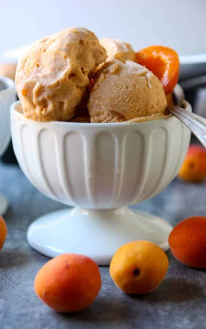 Two scoops of ice cream in a white bowl with a spoon