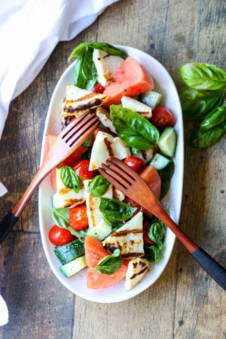 Grilled Halloumi & Watermelon Salad on a white platter with wooden salad forks