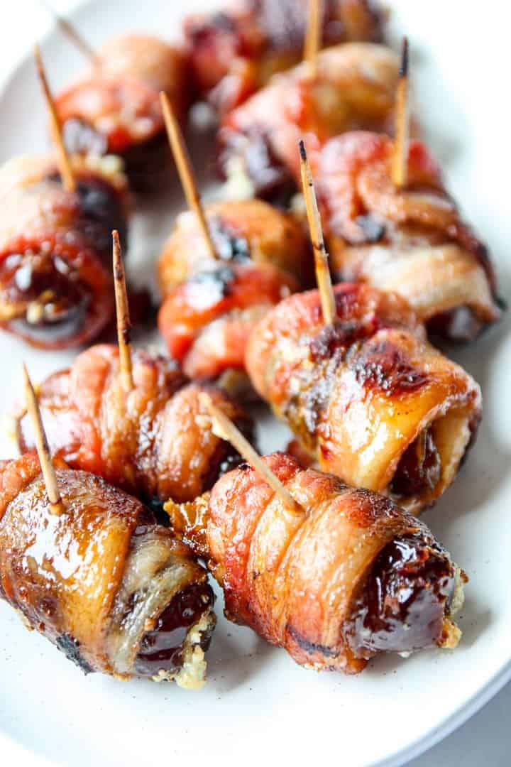Baked bacon wrapped dates with toothpicks on a plate