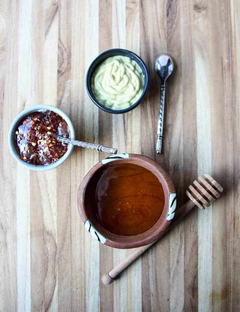 Small dishes of condiments on a wooden cutting board
