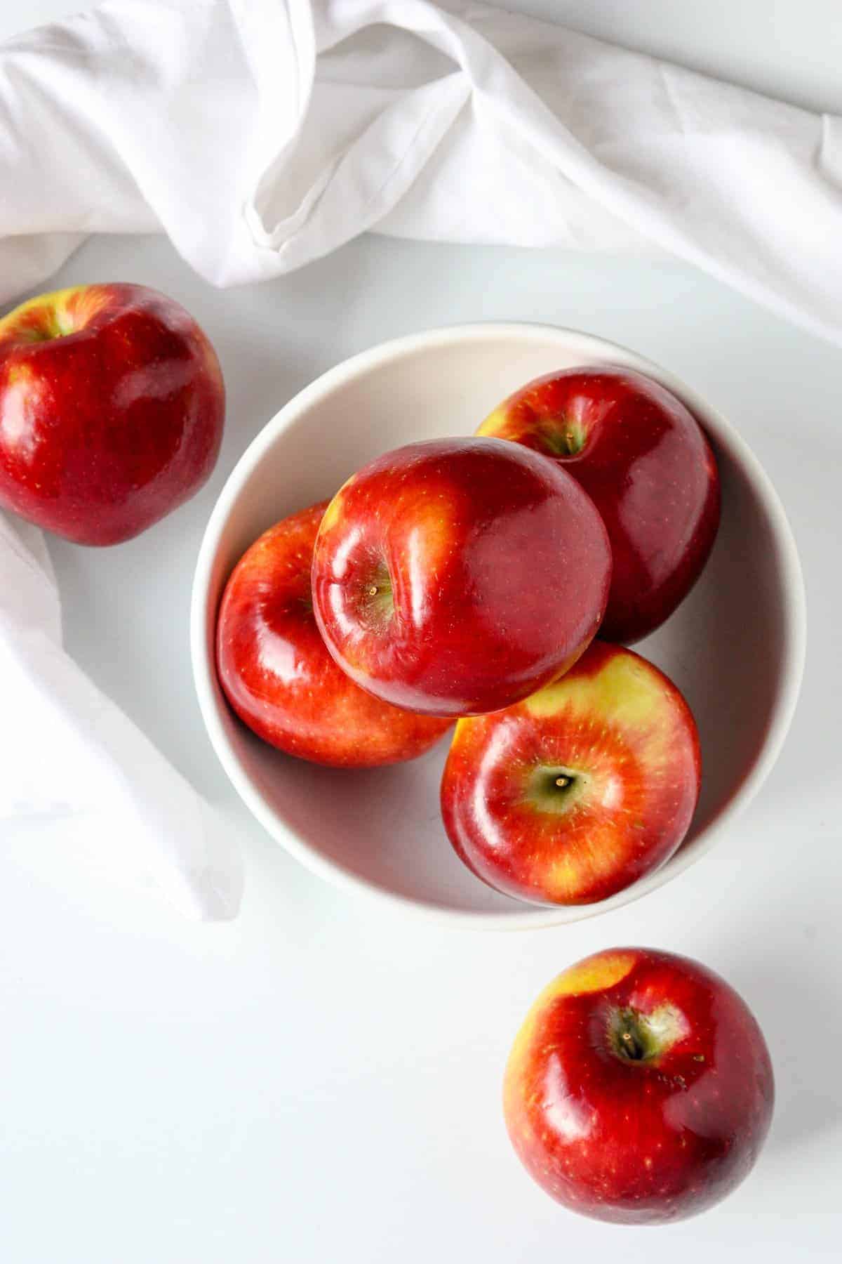A bowl of apples on a white table.