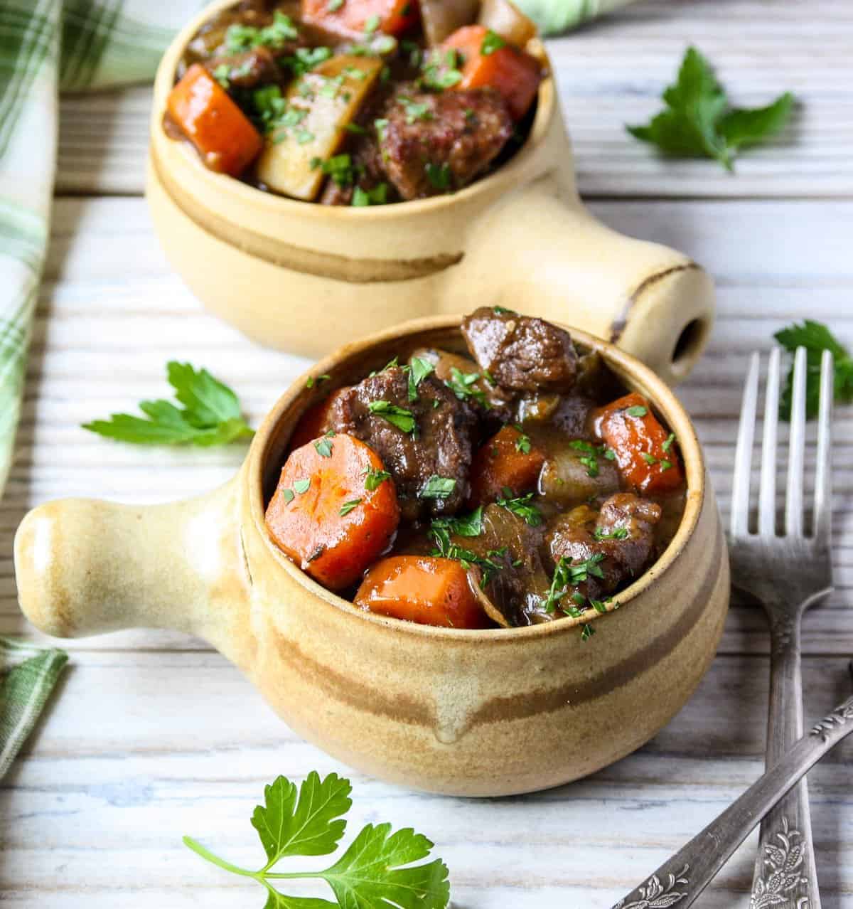 Two bowls of Irish beef stew on a white washed table.
