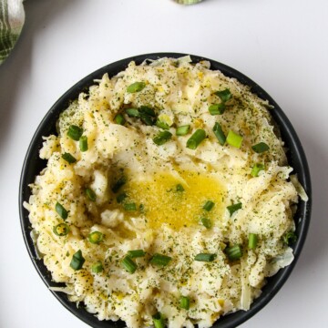 Irish Mashed Potatoes in a black dish on a white table.