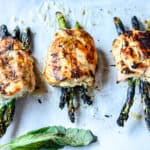 Three grilled asparagus stuffed chicken breasts on a tray.