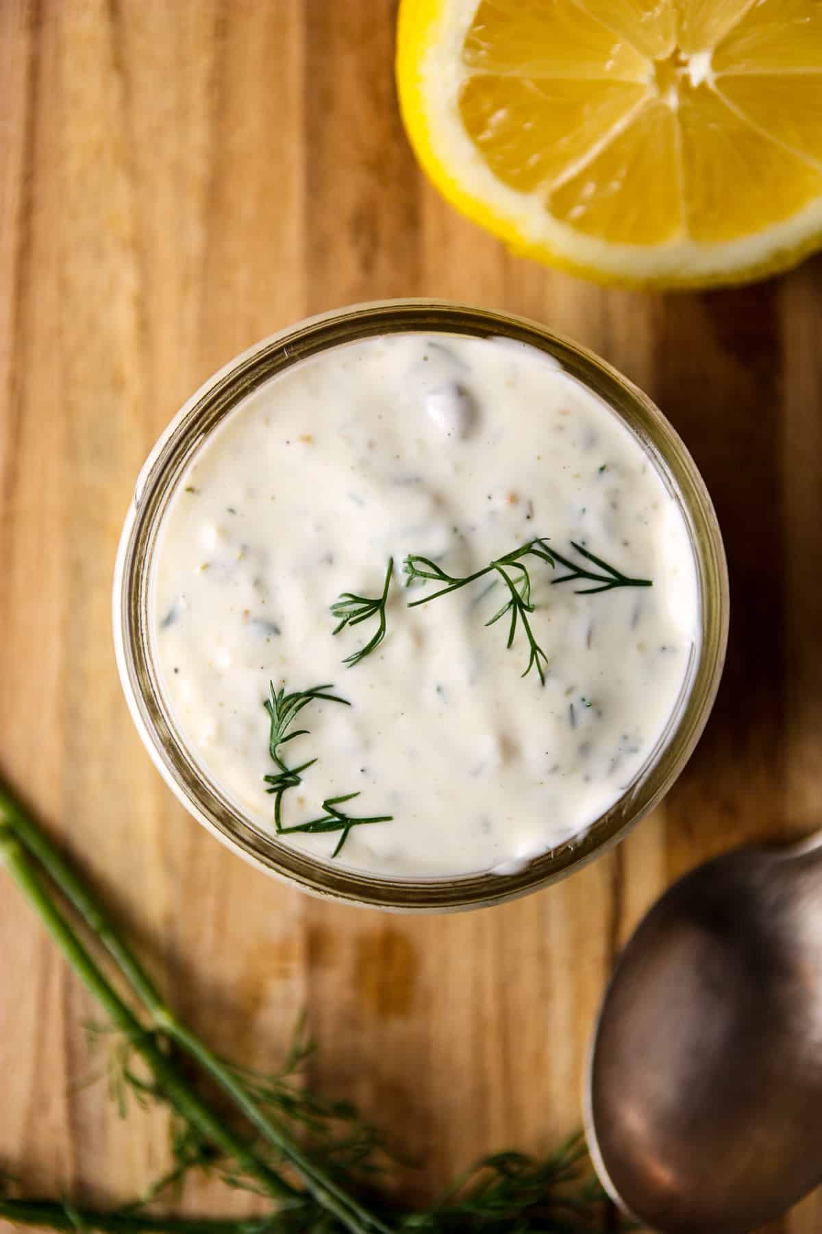 A jar filled with tarter sauce on a wooden board.