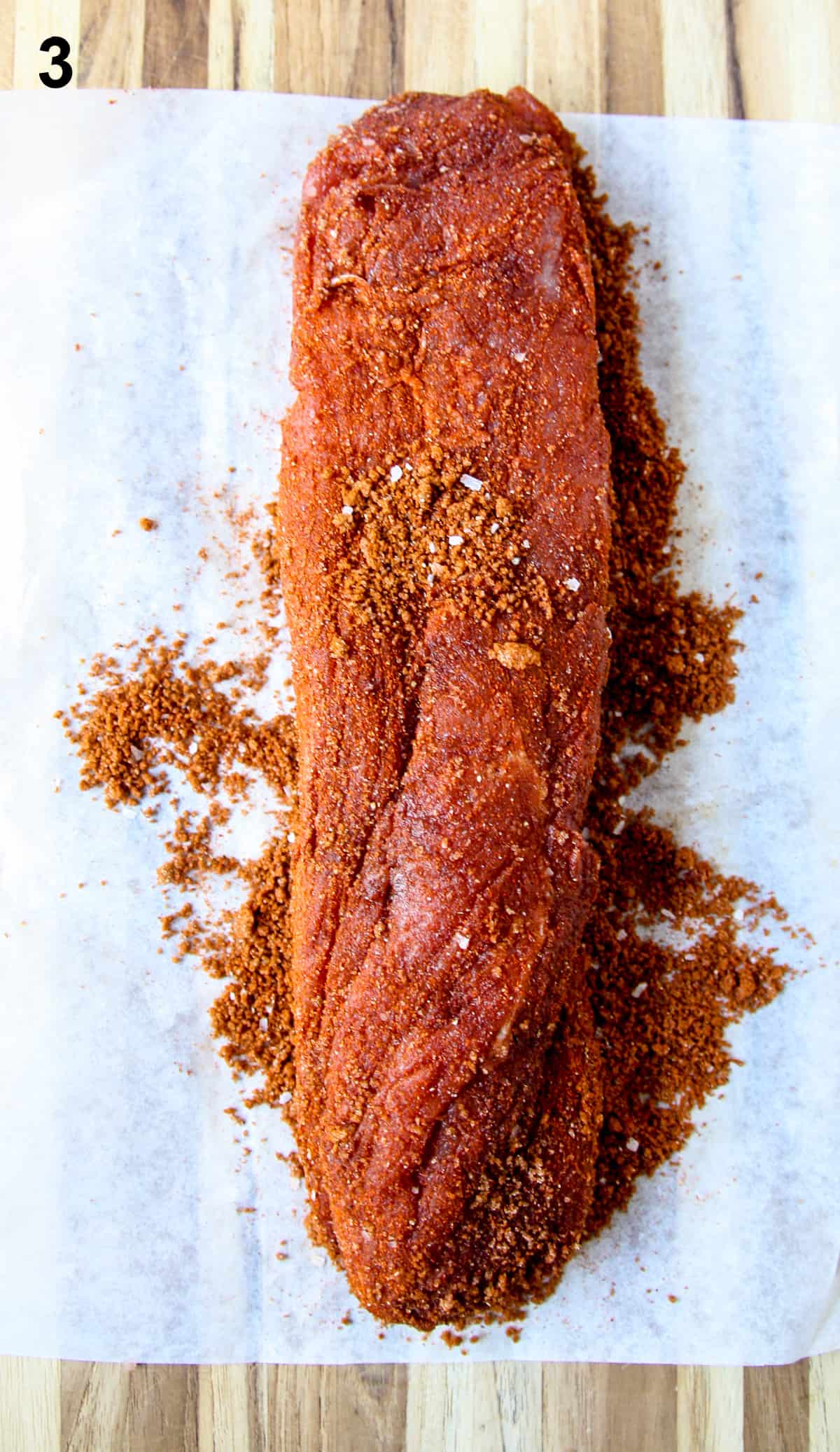 A raw pork tenderloin coated in seasoning rub.