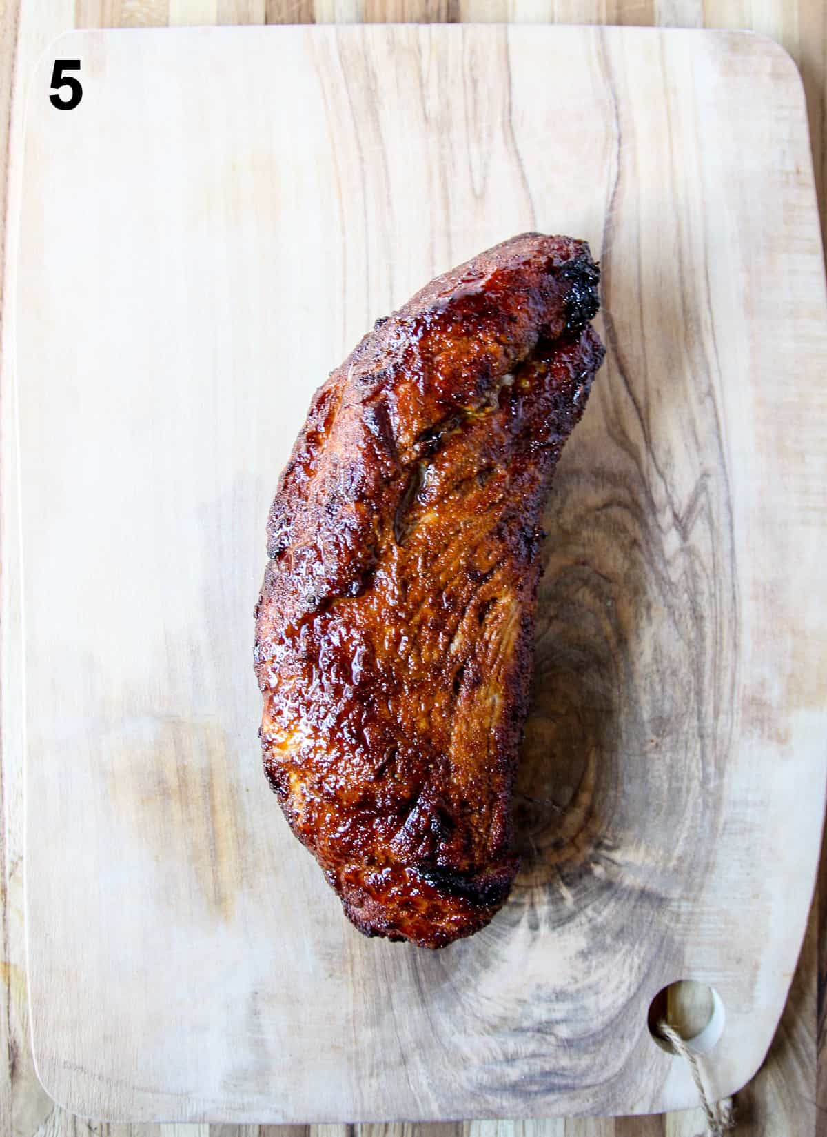 The cooked pork tenderloin resting on a cutting board.