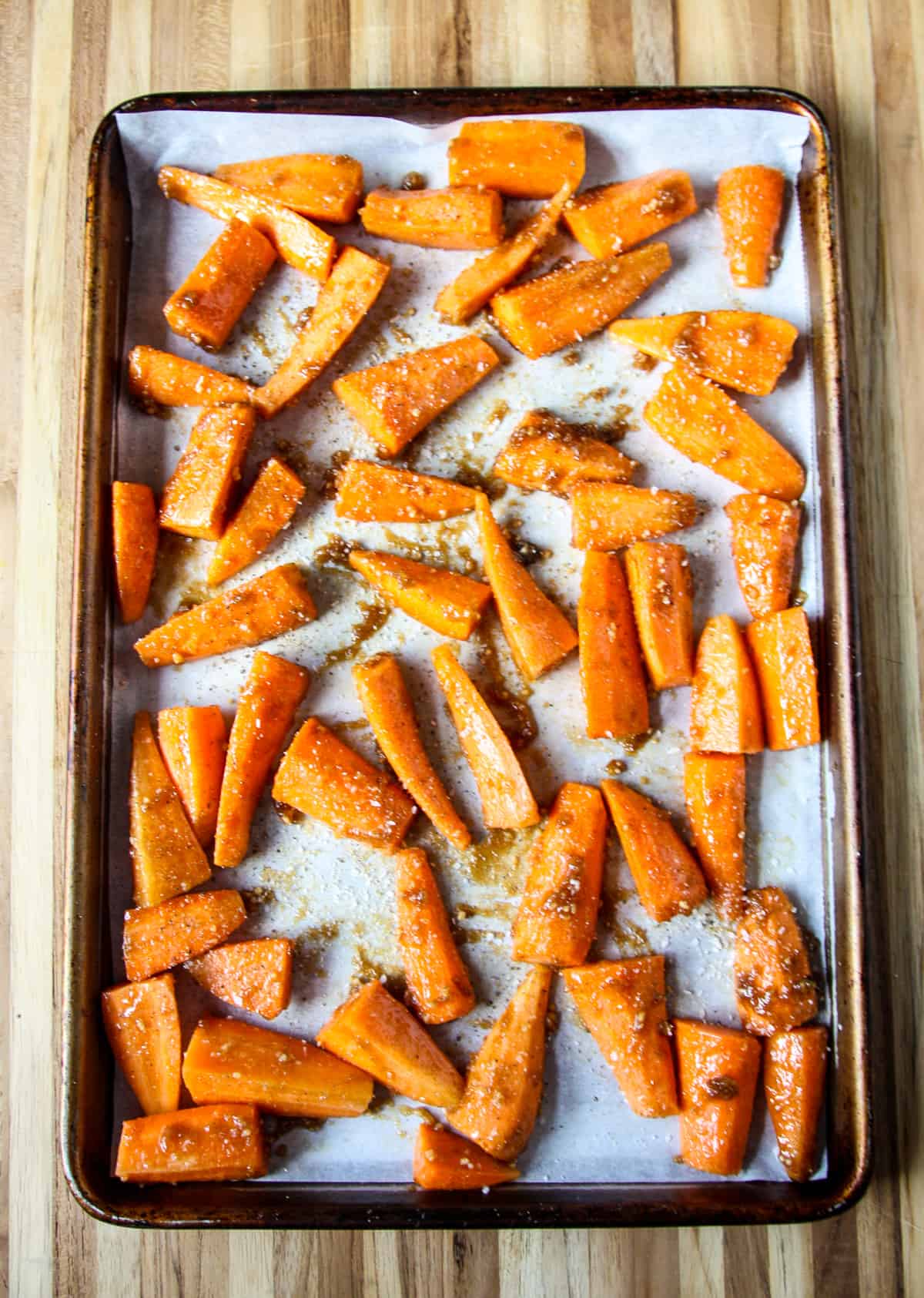 Brown sugar and butter glazed carrots on a baking sheet ready to go in the oven.