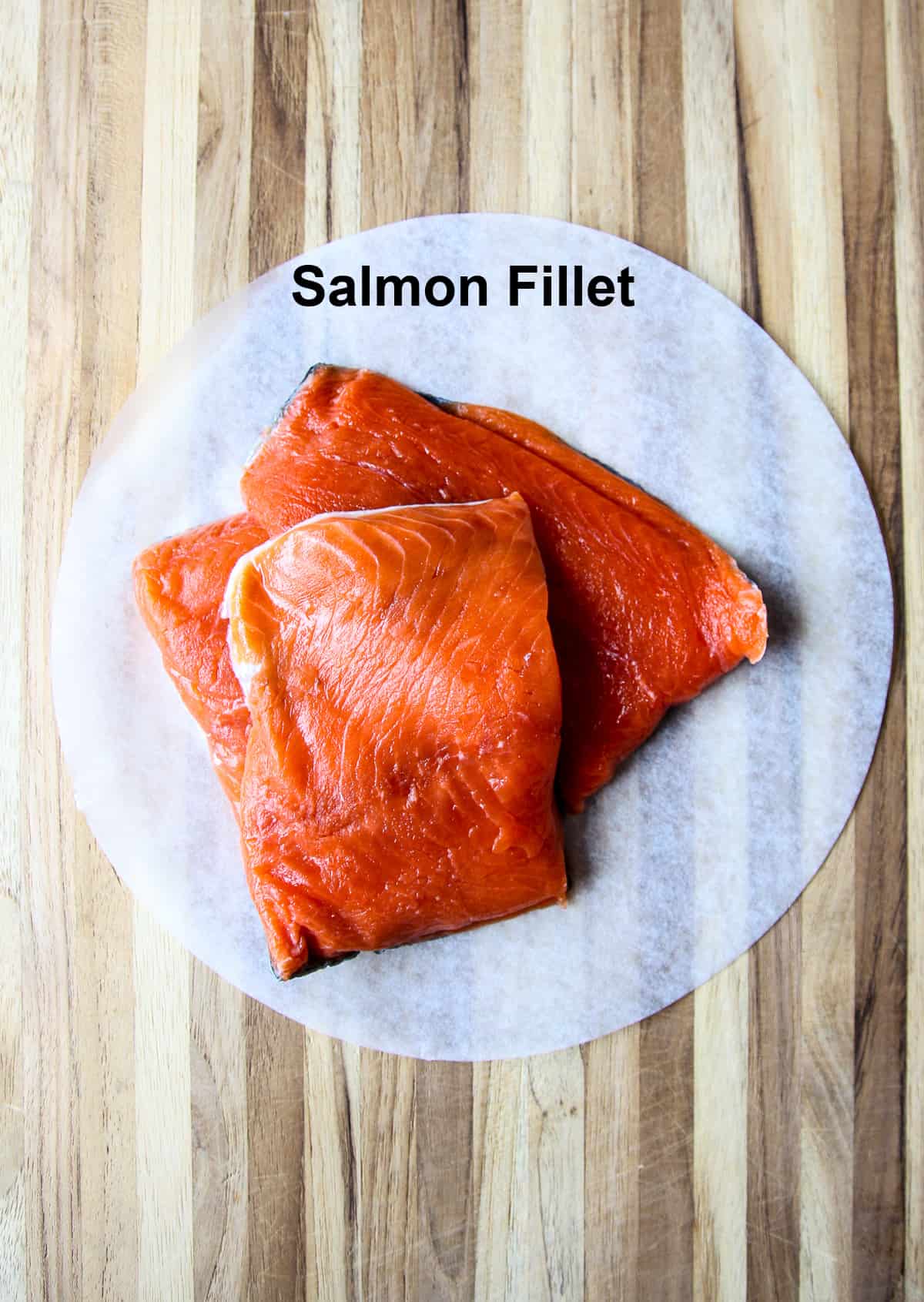 Uncooked salmon fillet pieces on parchment paper.