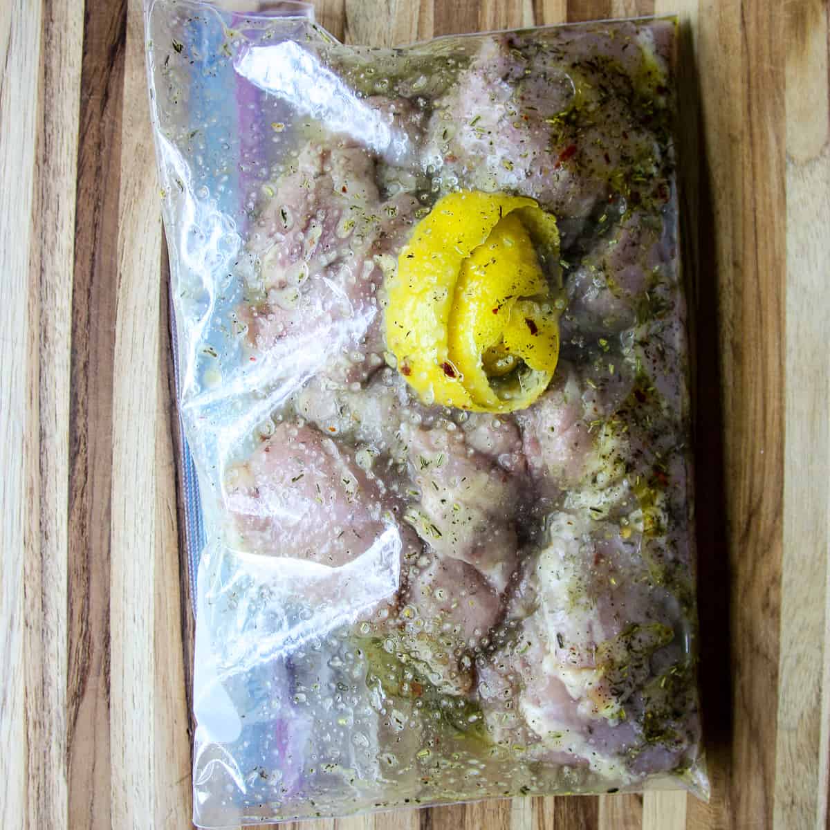 The raw chicken and marinade in a sealed freezer bag.