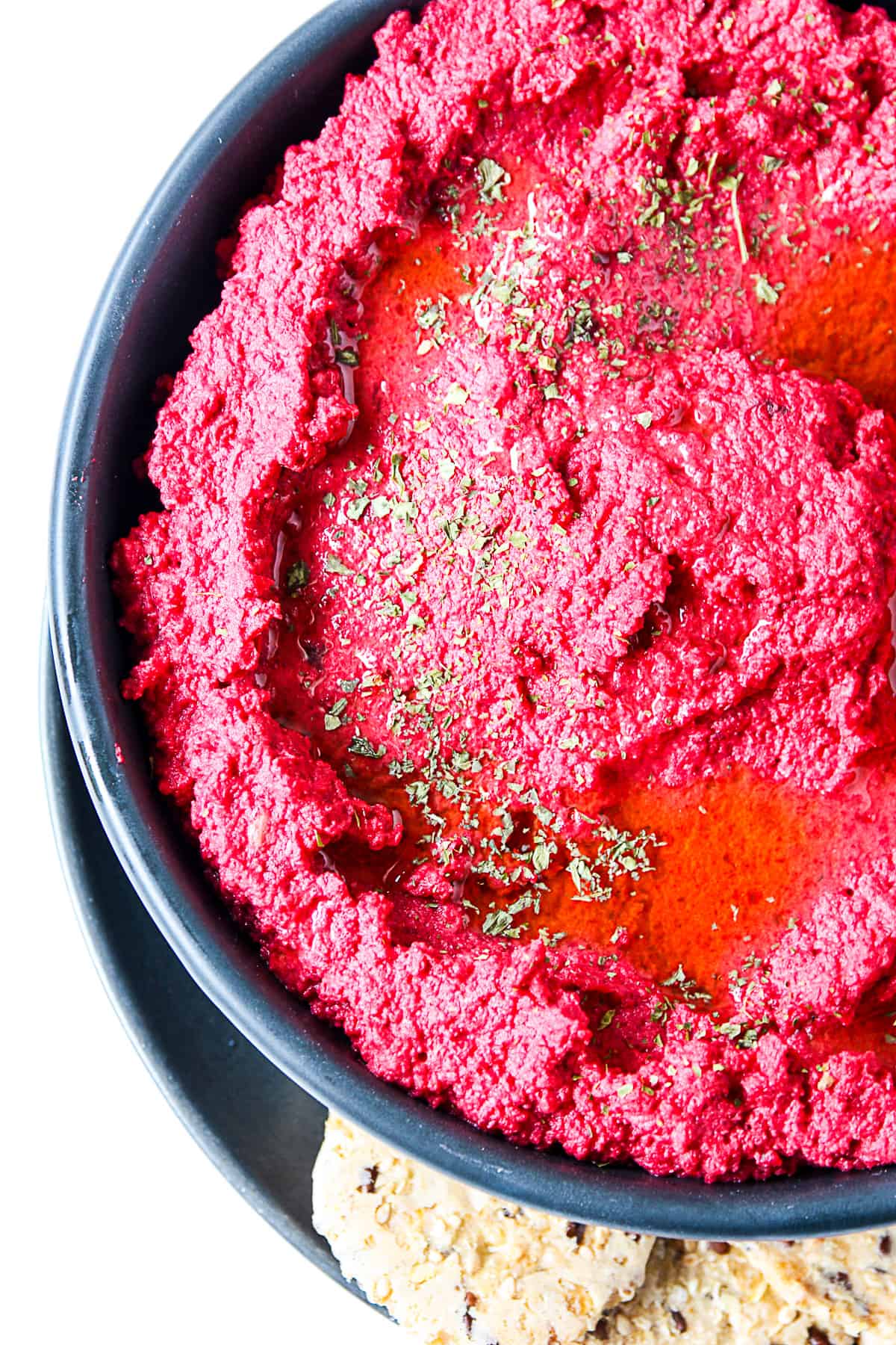 A closeup of roasted beet hummus in a black dish.