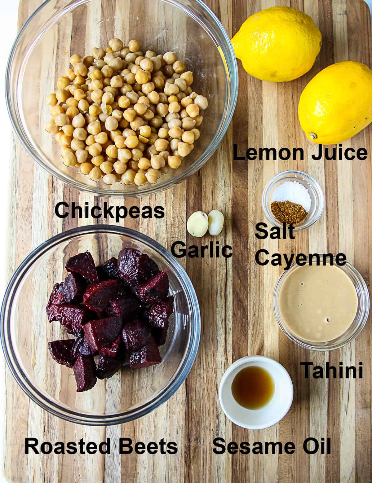 All of the ingredients to make roasted beet hummus on a wooden board.