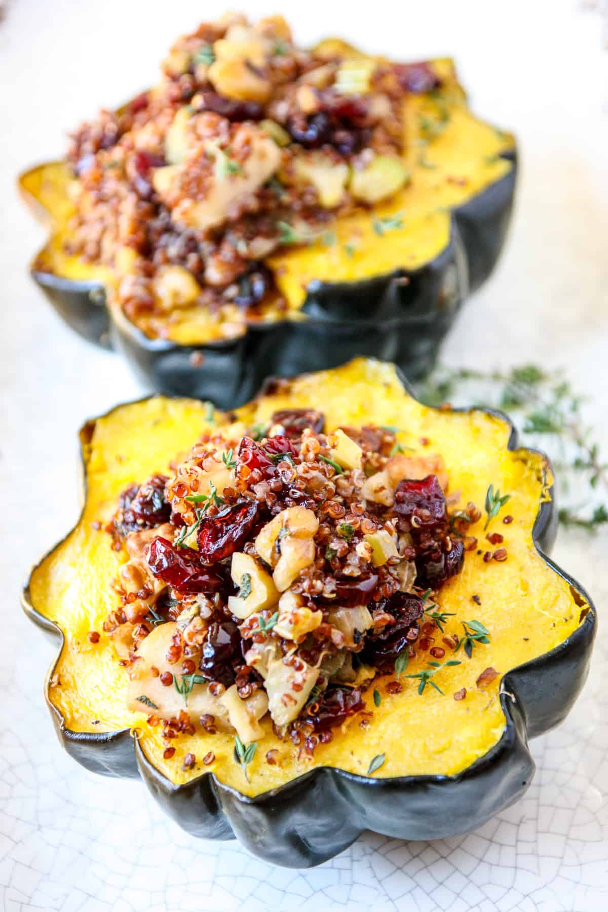 Two stuffed acorn squash halves on a white plate ready to serve.
