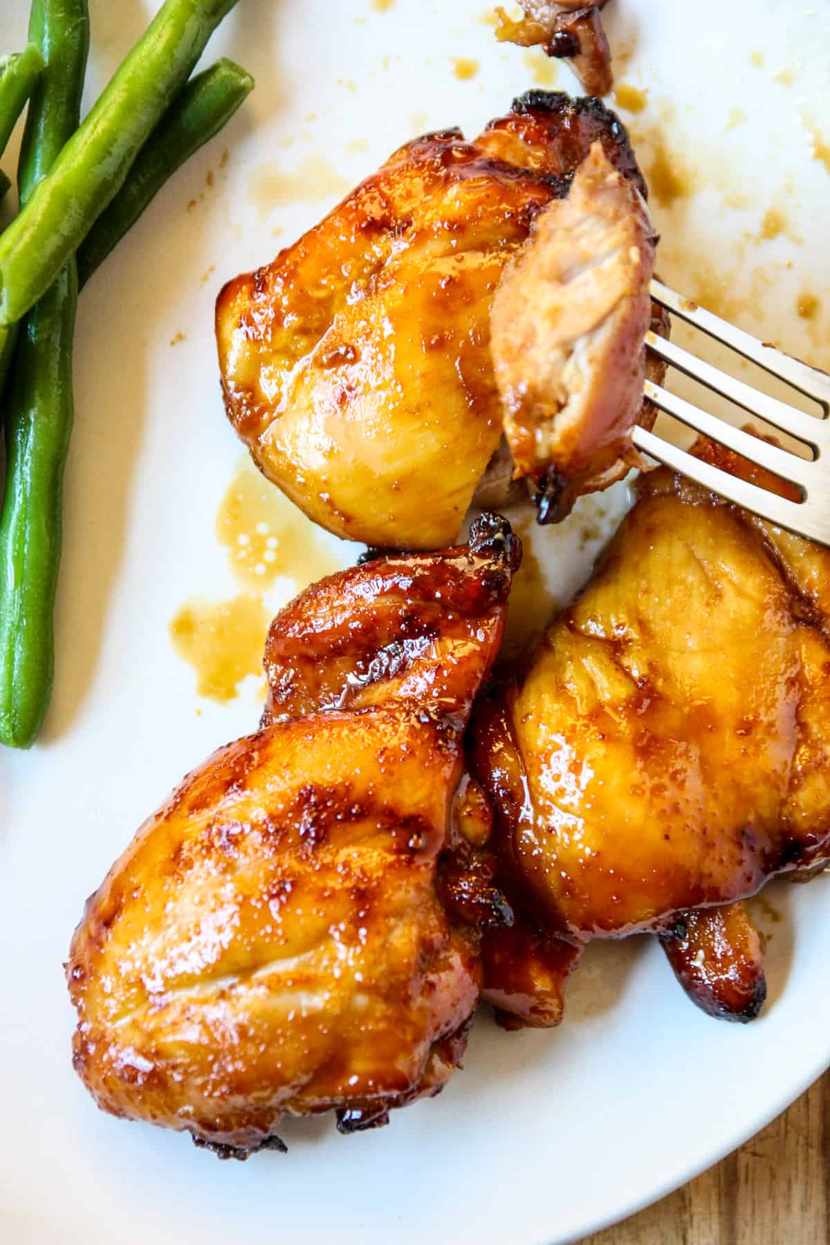 A silver fork with a piece of air fryer teriyaki chicken.
