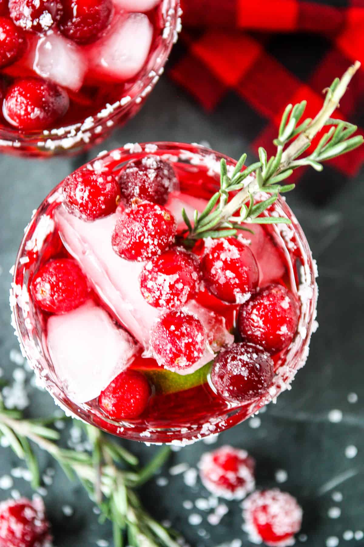 A glass of cranberry mistletoe margarita on a marble countertop.
