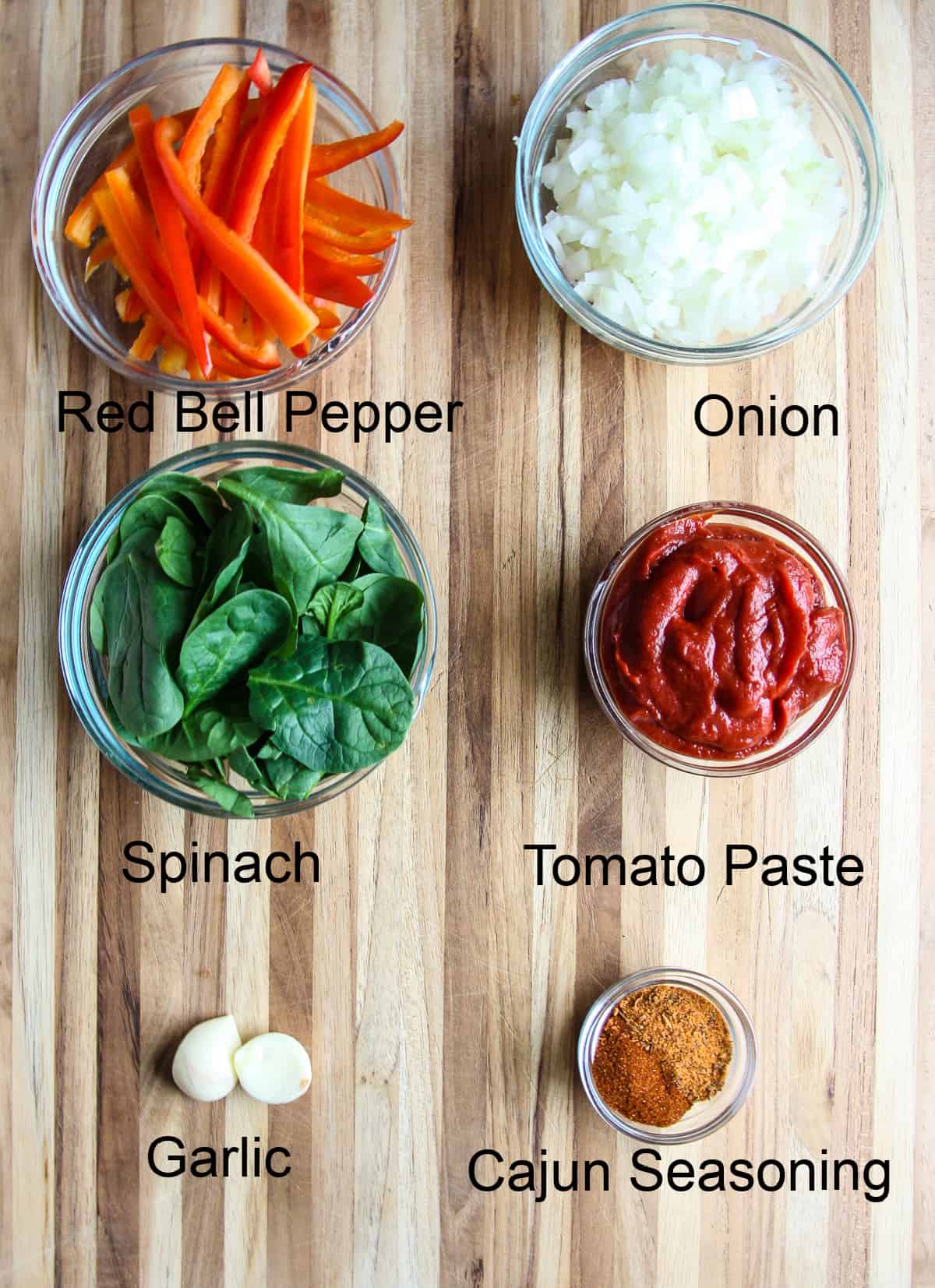 Vegetable, seasonings, and tomato paste on a wooden cutting board.