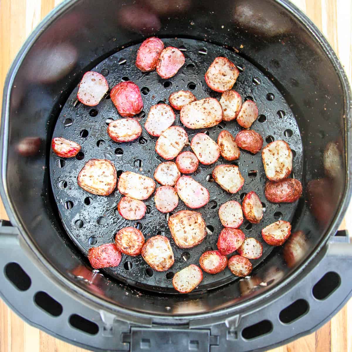 Cooked radish slices in the air fryer basket.