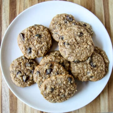 A dozen gluten free oatmeal raisin cookies on a white plate.