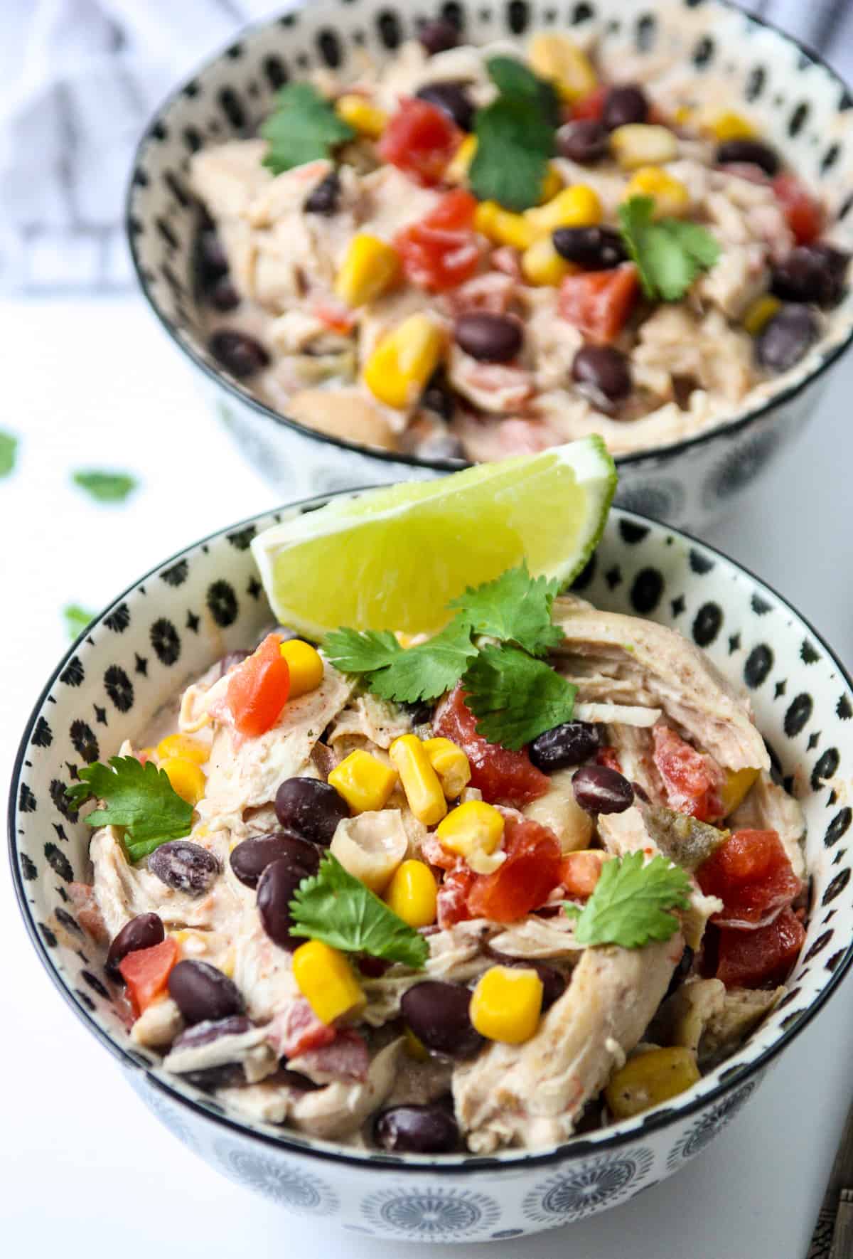 Two black and white bowls filled with slow cooked cream cheese chicken chili.