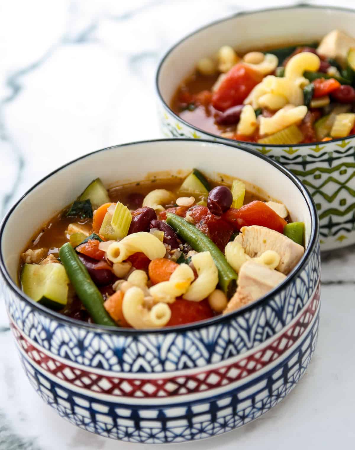 Minestrone soup in colorful patterned bowls.
