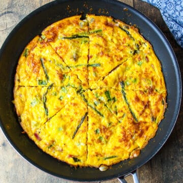 Baked ham and cheese frittata with asparagus in a skillet.