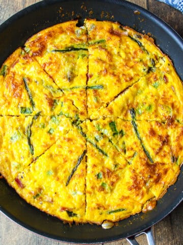 Baked ham and cheese frittata with asparagus in a skillet.