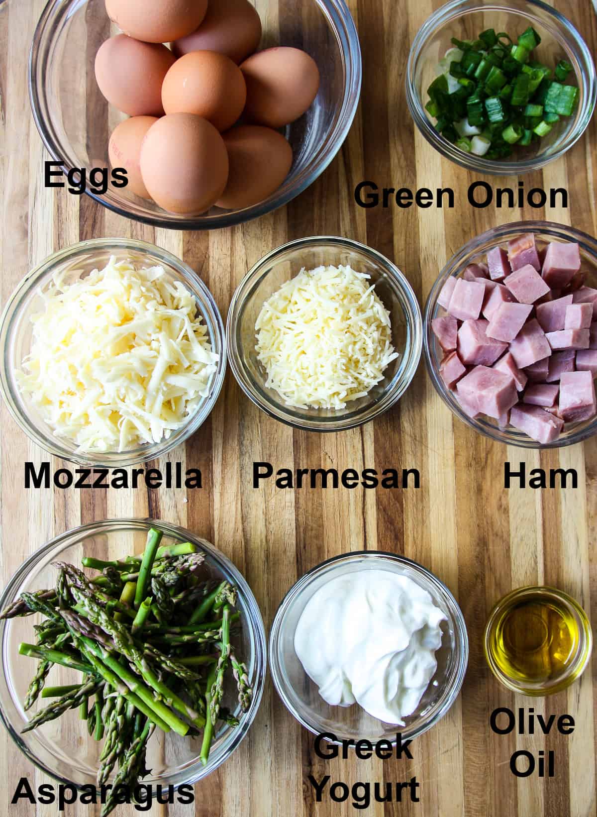 All of the ingredients for making the frittata in glass dishes on a wooden board.