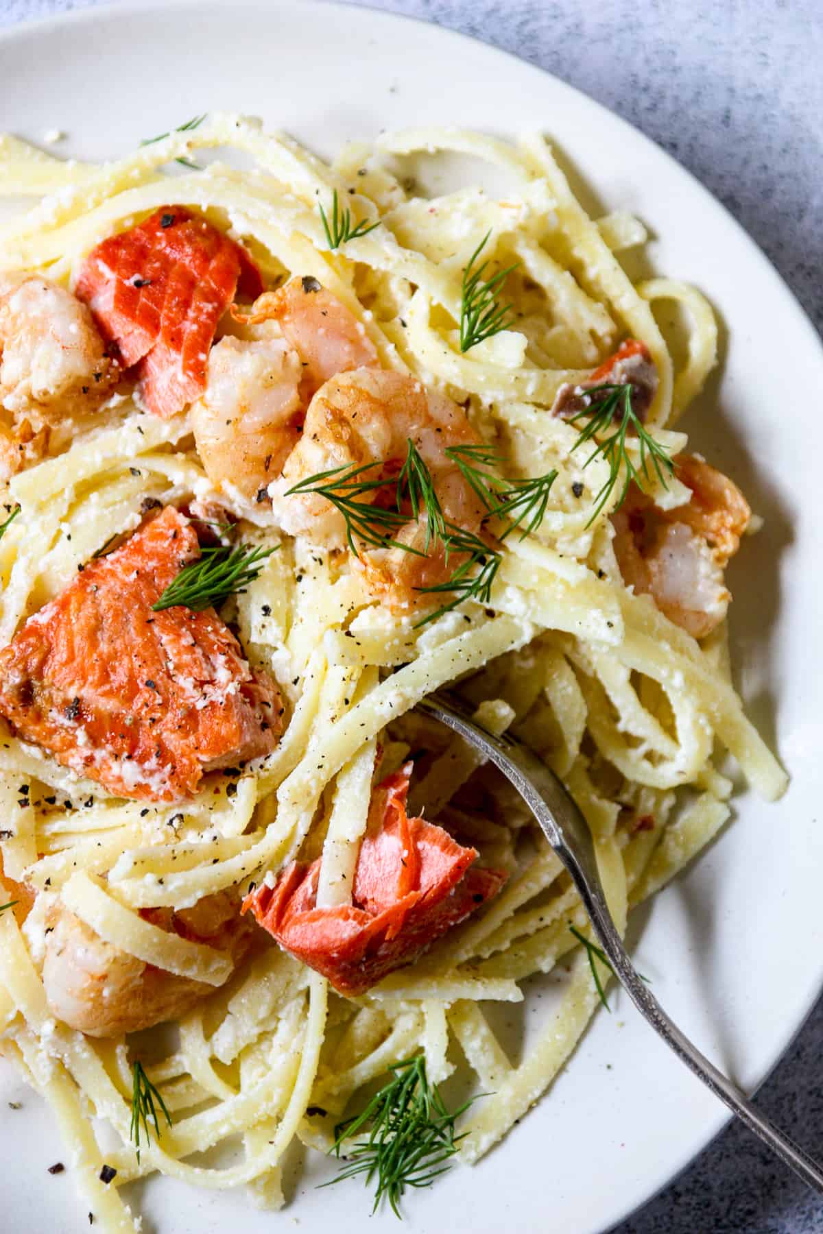 A fork twirling in a plate full of seafood fettuccini.