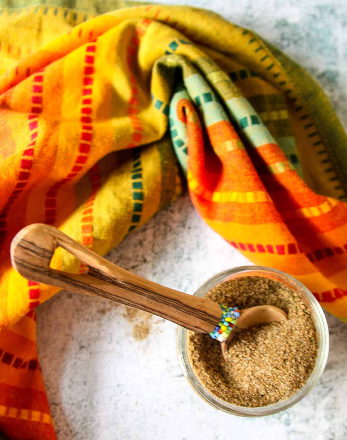 A jar of Jamaican jerk seasoning with a small wooden spoon in it.